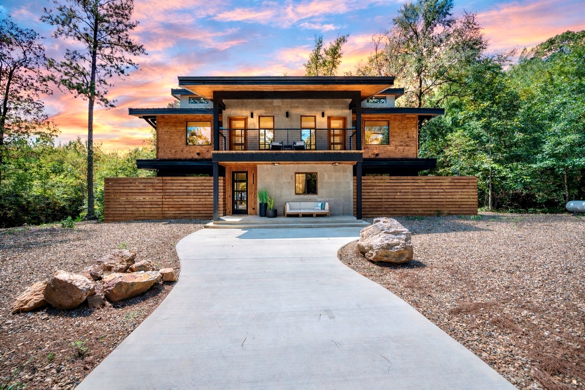 Your Hochatown getaway starts here—sleek design, peaceful woods, and a picture-perfect entrance at golden hour.
