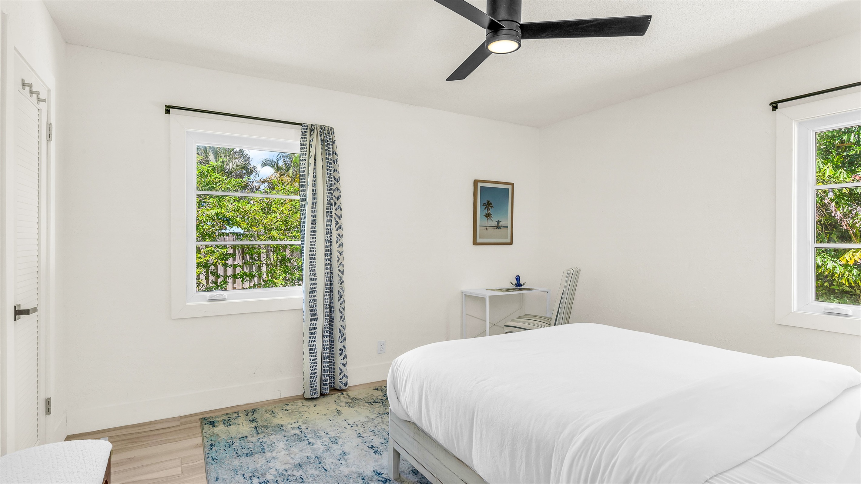 Bedroom 3 features bright coastal decor, crisp white linens, and pops of ocean blue- creating a serene and cheerful retreat for guests to relax and unwind in comfort.