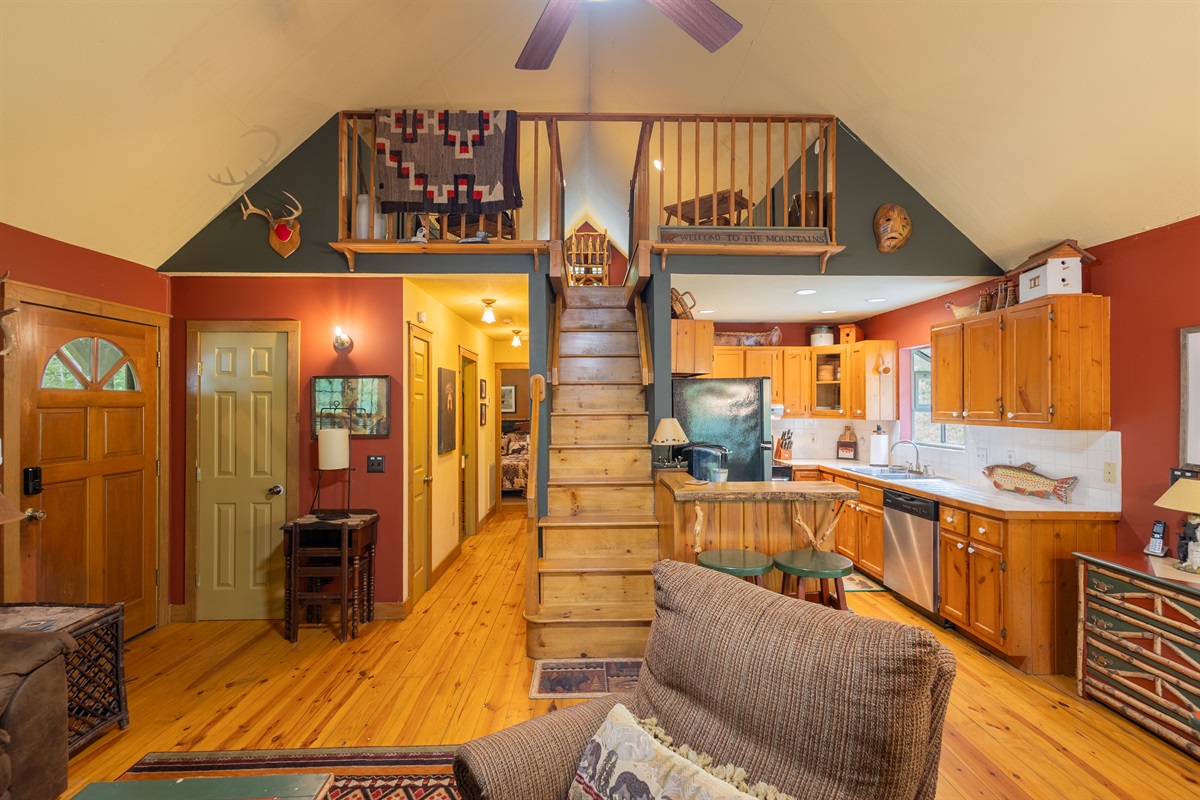 From the center of the living room, the open layout connects seamlessly to the loft, kitchen, and hallway areas above and beyond.
