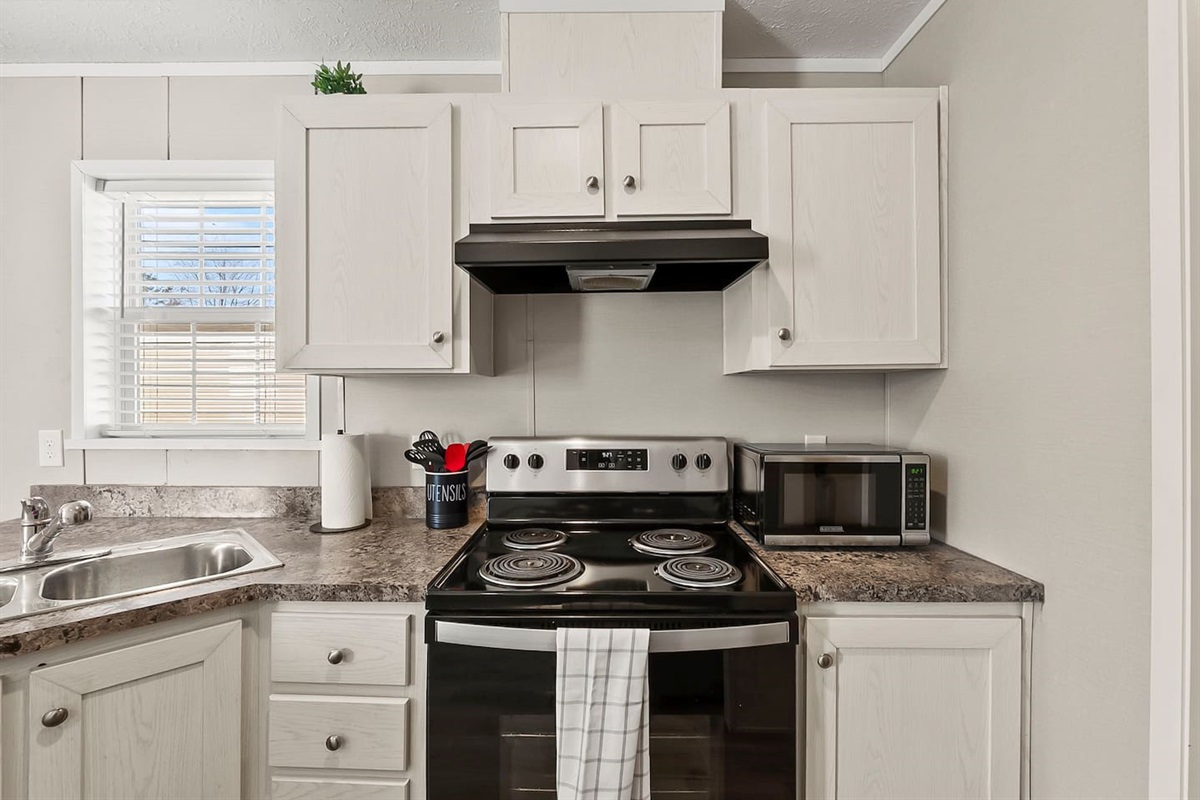 Clean and functional kitchen setup with stove, microwave, and storage—perfect for preparing meals during your stay.