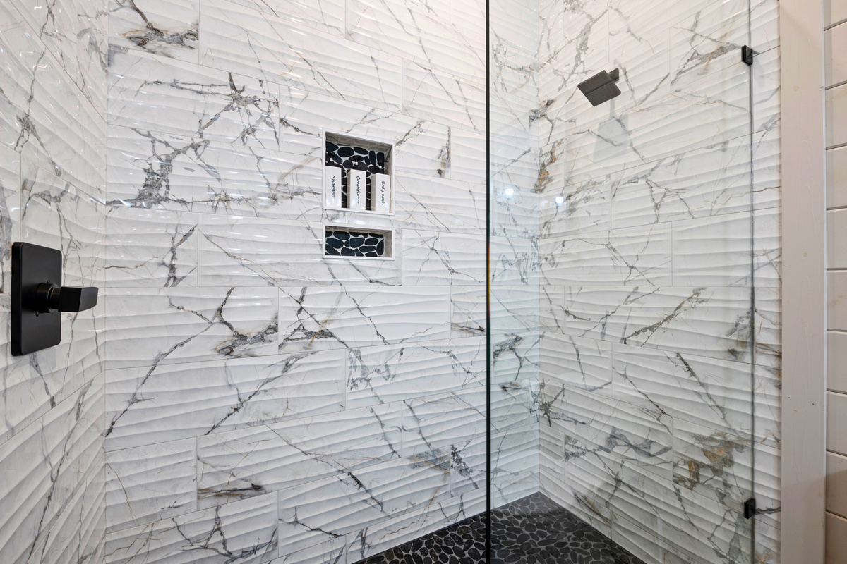 The oversized walk in shower offers a spa like experience with beautiful marble inspired tile and plenty of room to refresh.