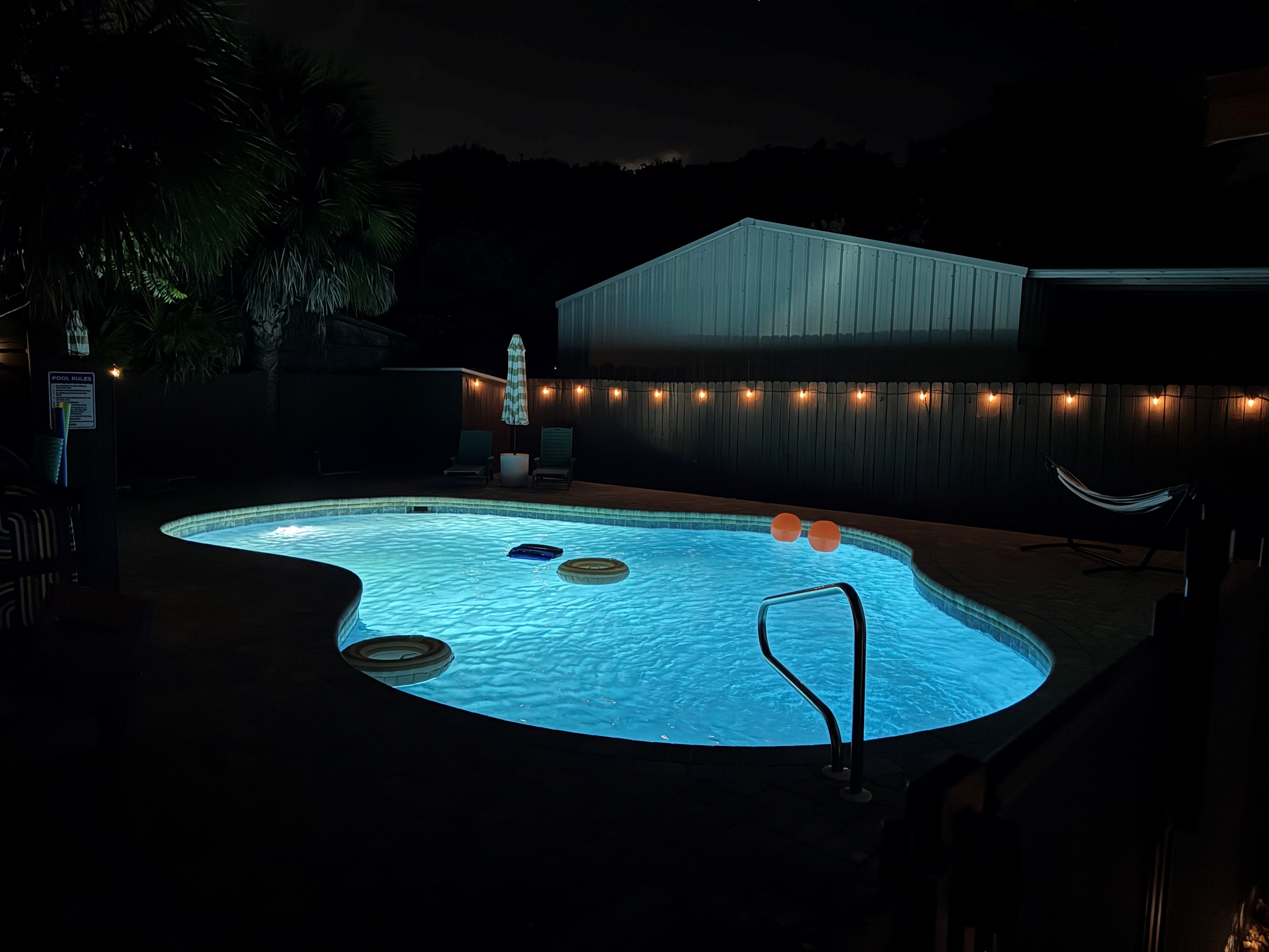 Swim after dark. The pool glows blue with underwater lighting while string lights flicker overhead, turning your backyard into the best bar in PCB.