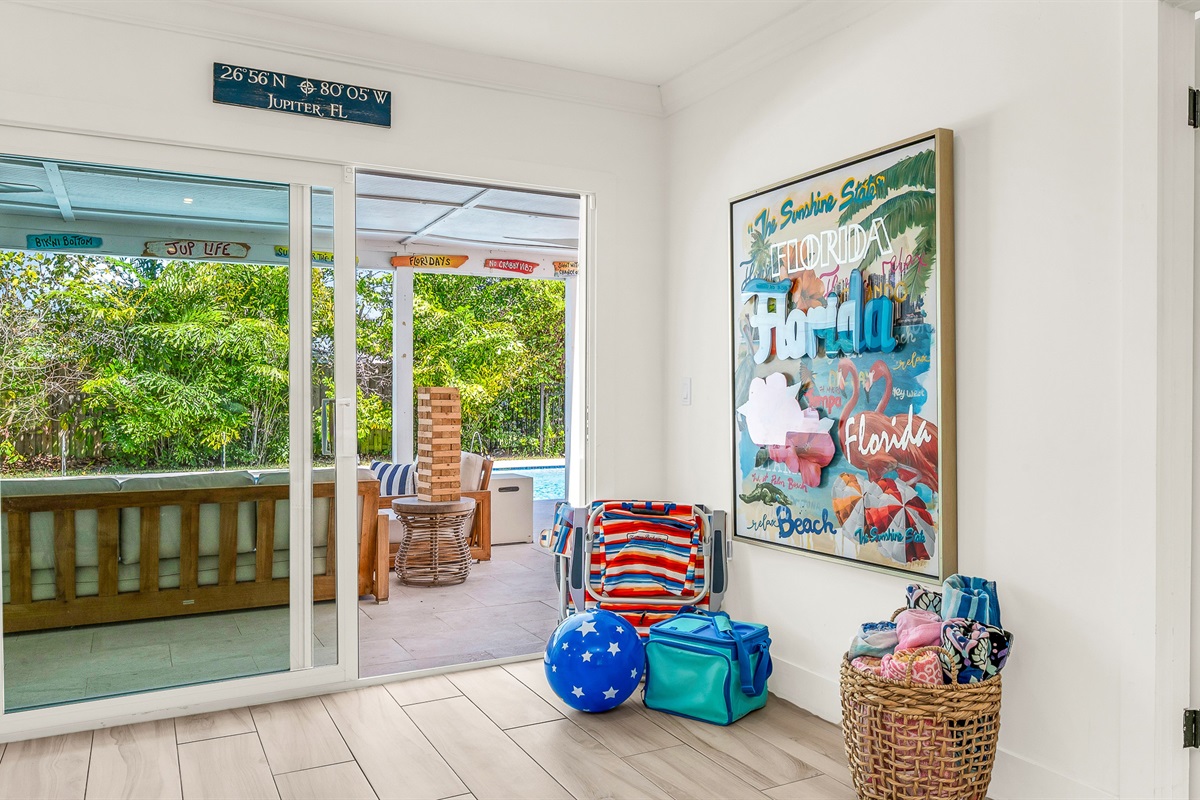 This cheerful coastal corner is thoughtfully stocked with beach essentials, ready for a day of sun and relaxation.  Bright artwork and natural textures create a welcoming vibe that perfectly complements this luxury Airbnb's laid-back seaside style.