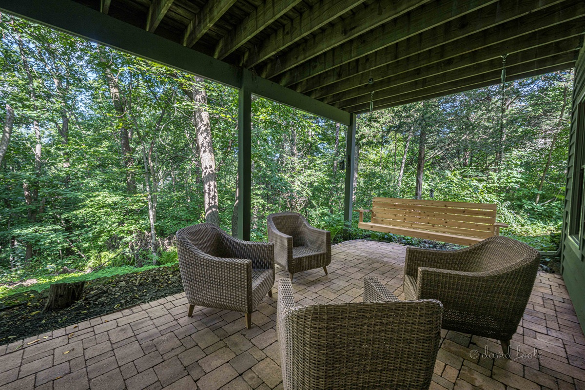 Covered patio with gas fire table, seating, and porch swing