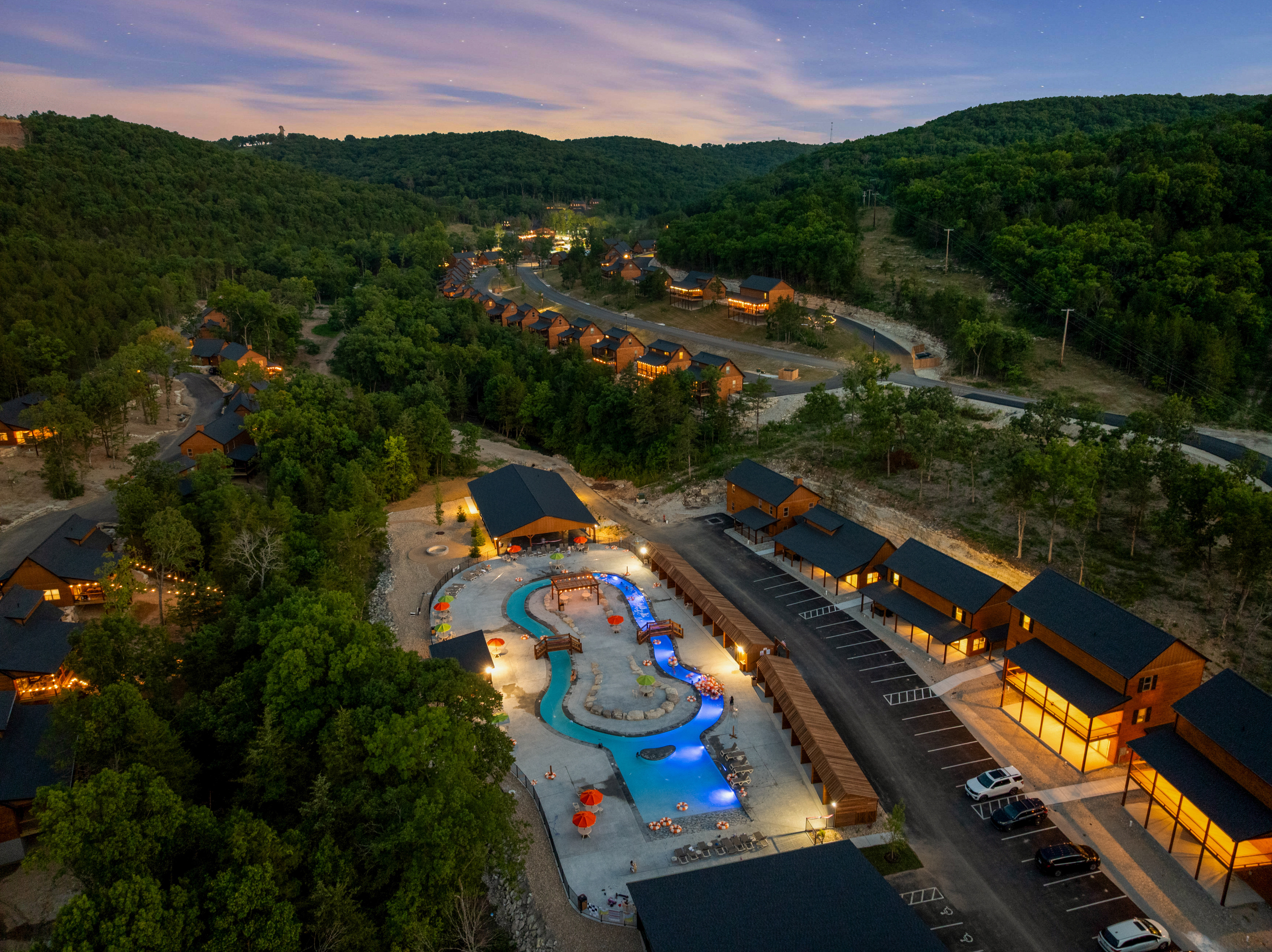 The Tall Timbers Camp lazy river and pools light up electric blue at night, just down the hill from Lone Star Lodge.