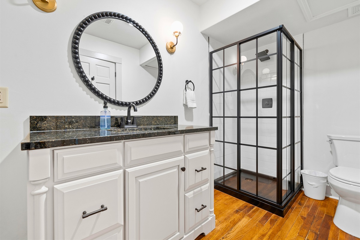 A modern bathroom with a stylish vanity and a black-framed walk-in shower offers both comfort and functionality.