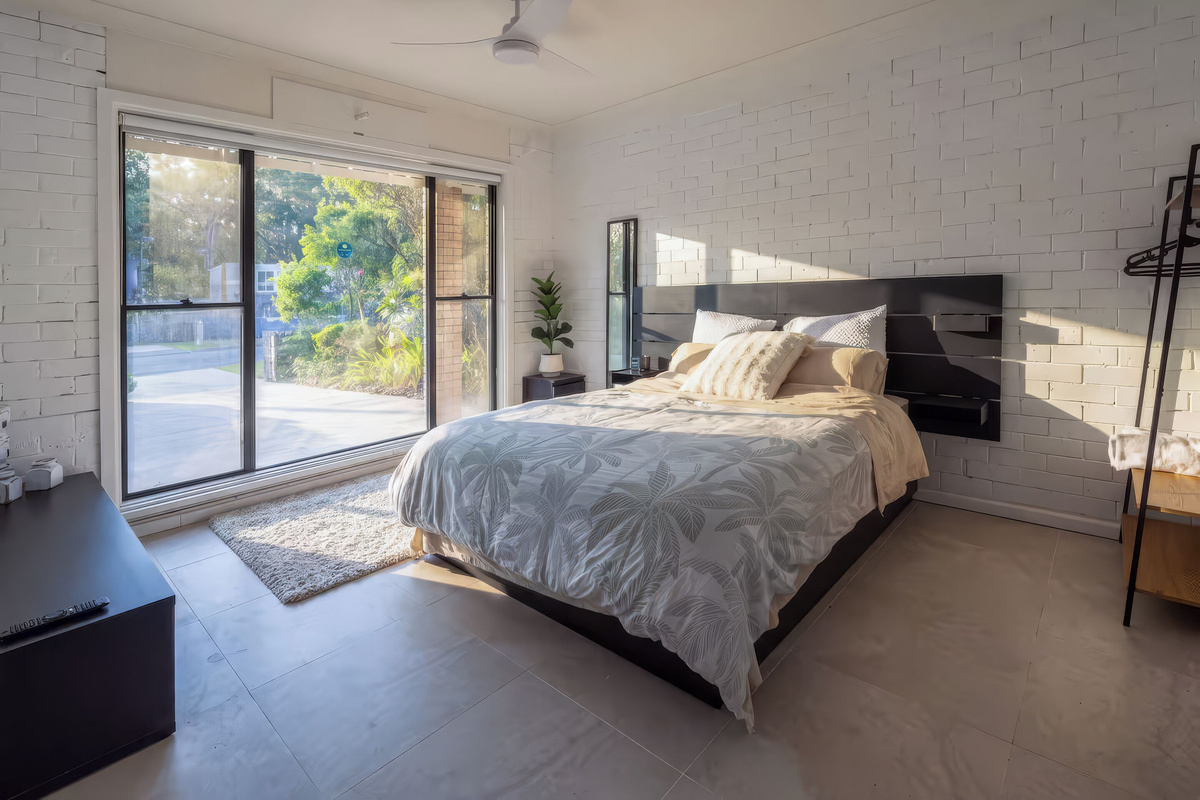 This queen bedroom at Luna’s Sanctuary features a ceiling fan, TV, storage space and sliding glass doors opening toward the front garden.