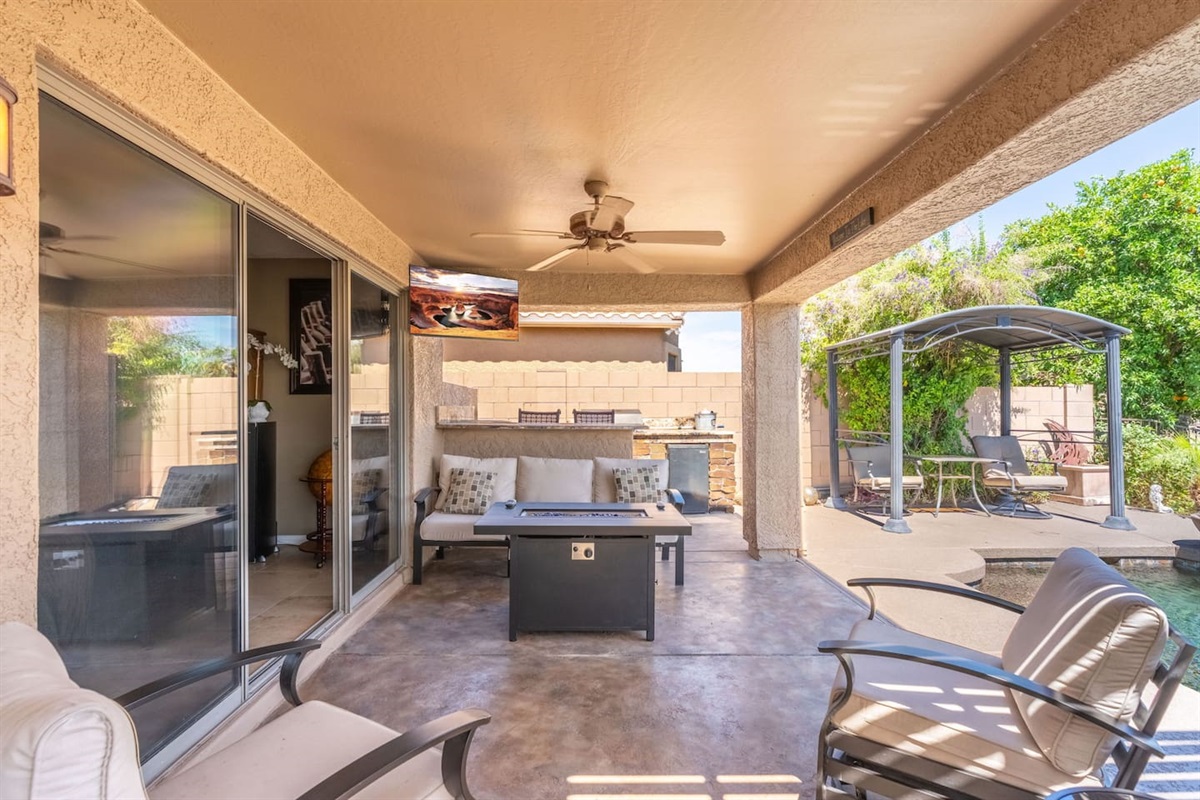 A wall-mounted outdoor TV, ceiling fan, and fire table make the covered patio a true all-season hangout — watch the game outside or just enjoy the warm evening air with the group.
