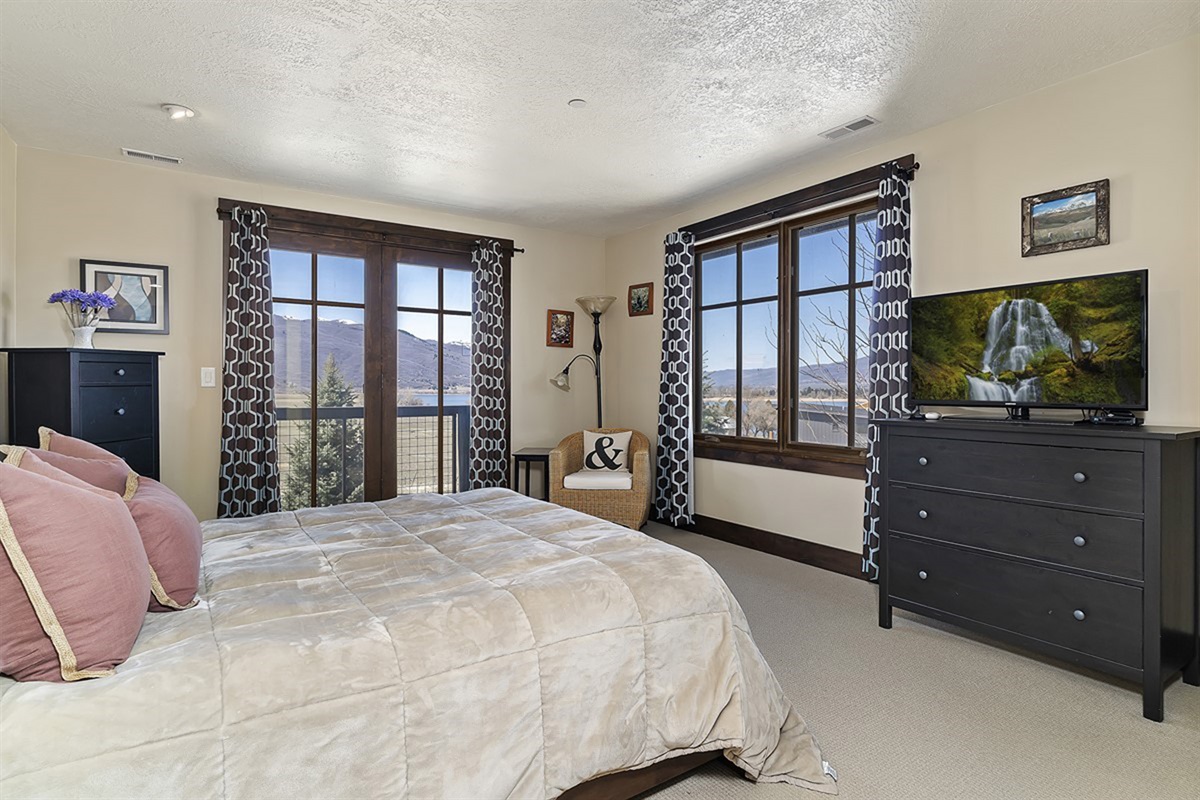 A serene primary suite featuring a plush king bed, expansive windows, and refined finishes—offering a peaceful retreat framed by natural beauty.