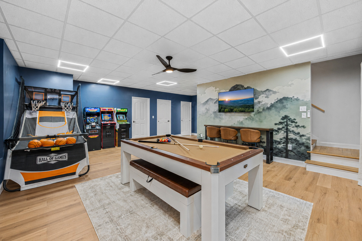 Spacious game room with pool table / ping-pong table, arcade games, basketball, and bar seating.