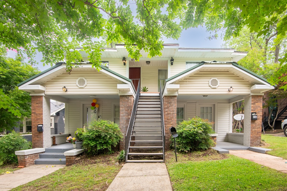Charming exterior with inviting curb appeal – A cozy duplex-style home with covered front entry and a shared green lawn.