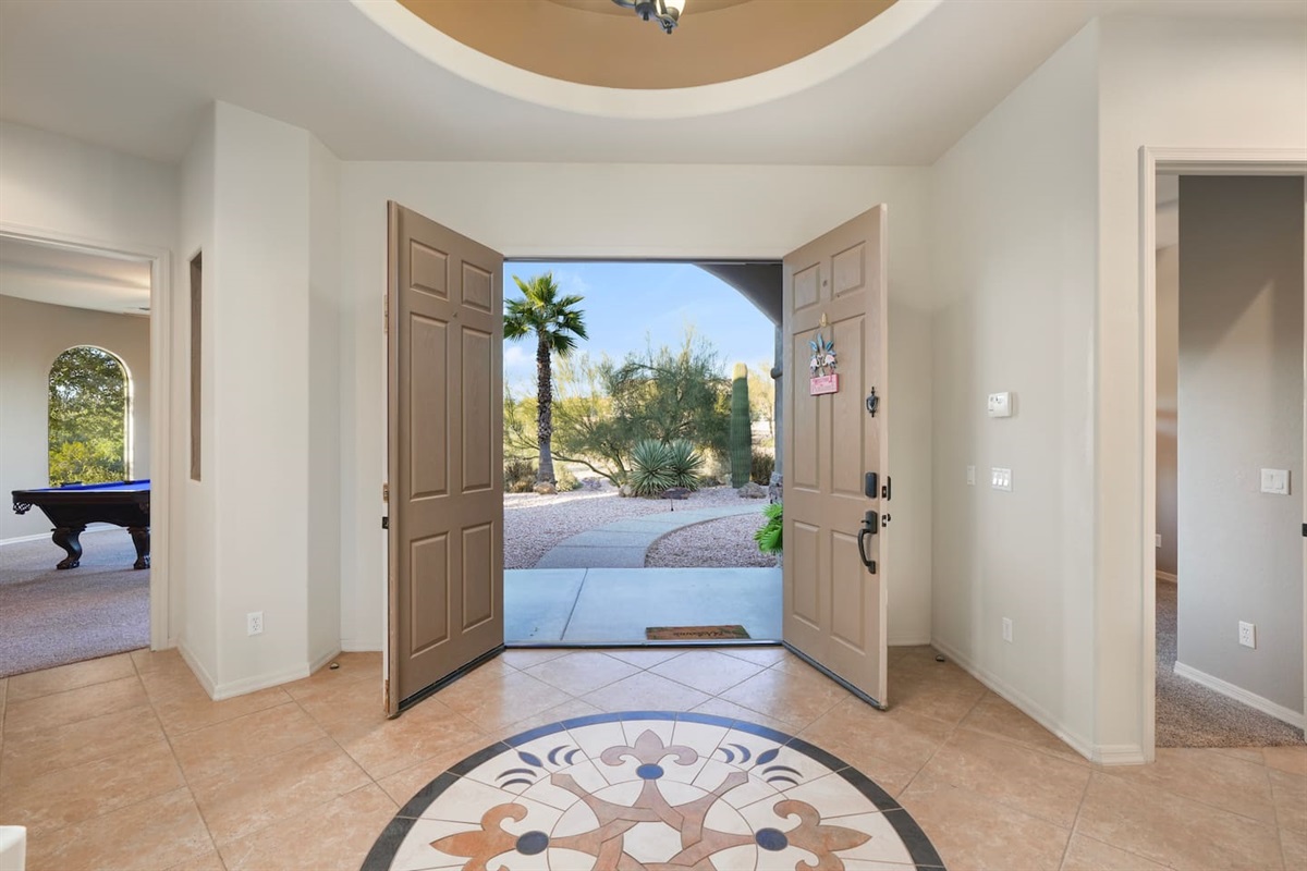 Grand entryway with double doors, decorative tile inlay, and abundant natural light.