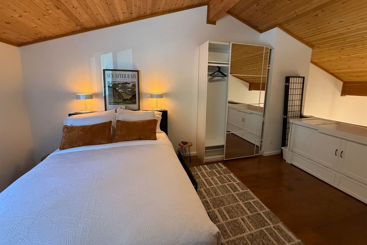 Upper Loft Bedroom: A bright, private bedroom suite with a cozy queen bed, excellent natural light, and convenient access to an en-suite bathroom and closet storage.