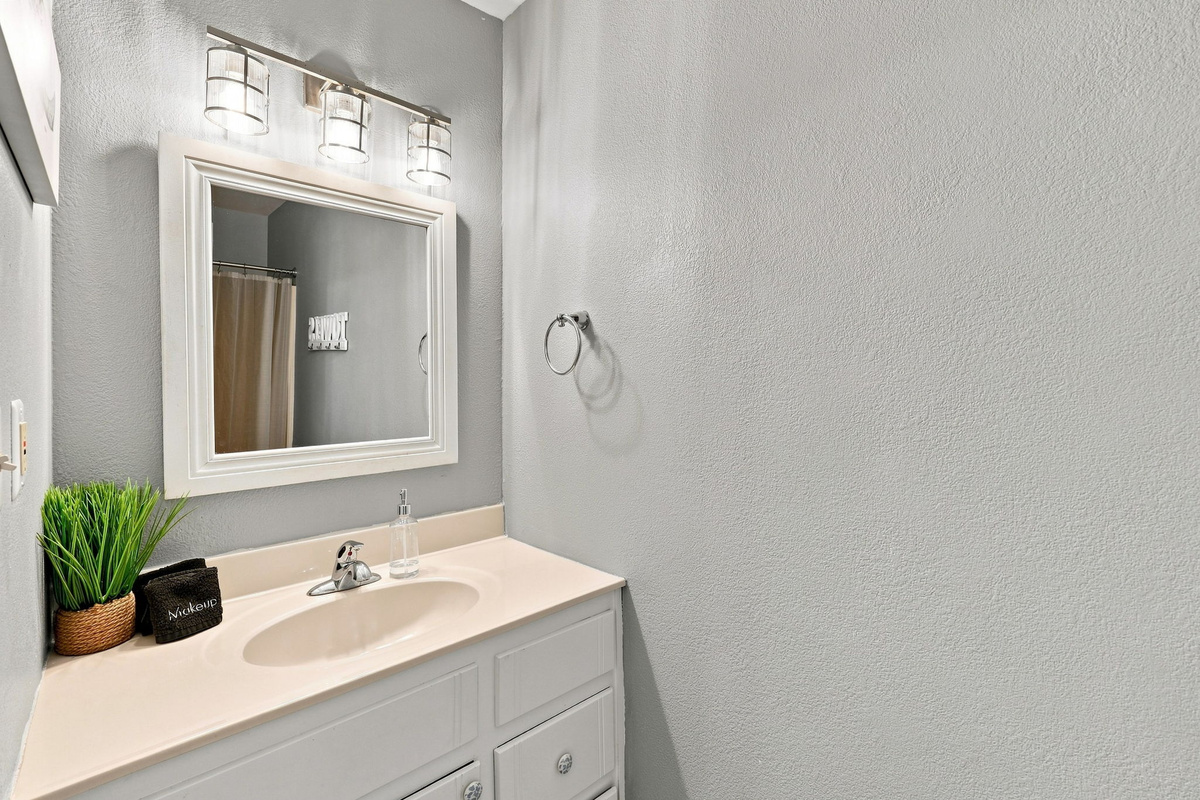 A clean, modern vanity space featuring warm lighting and a charming coastal accent plant.