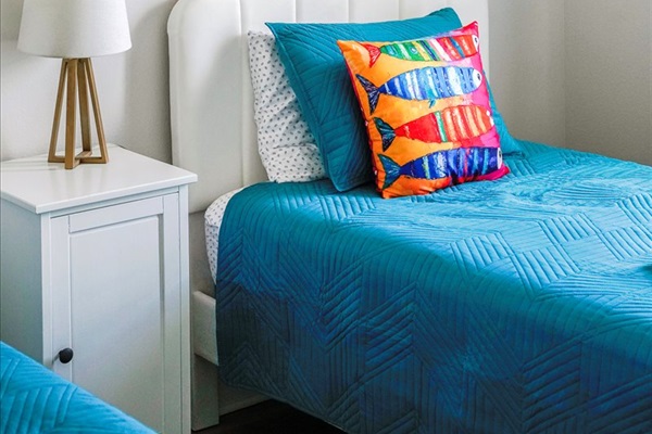 Relax in this charming Twin Bedroom with soft linens, nightstand, and a lamp