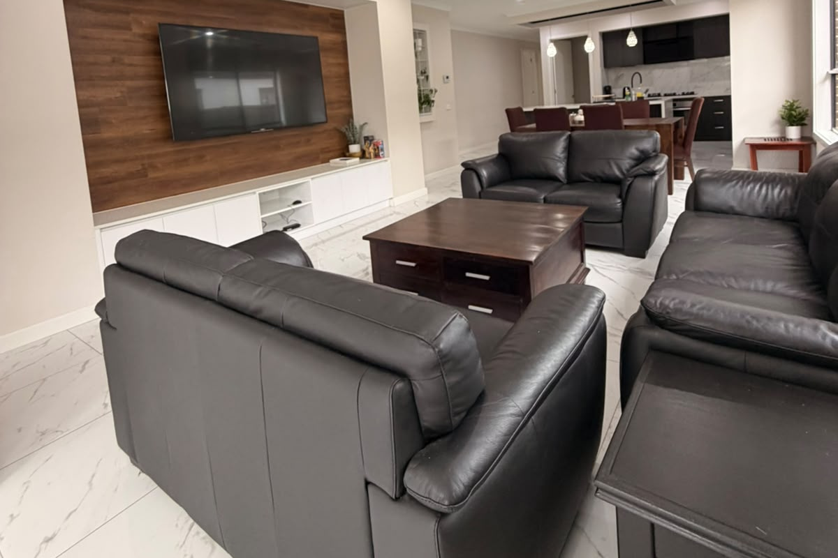 The timber TV feature wall and gloss tiled floors give this living area a polished, welcoming feel at Willows Stays Holiday.