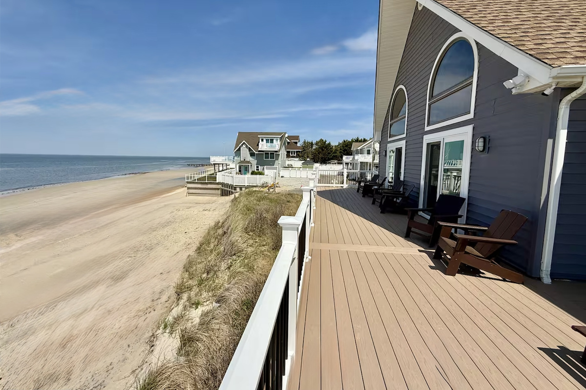 You can enjoy a scenic beachfront view from the property's spacious, elevated deck. This outdoor area is perfectly furnished with lounge chairs, offering an ideal space to relax and experience the coastal environment.