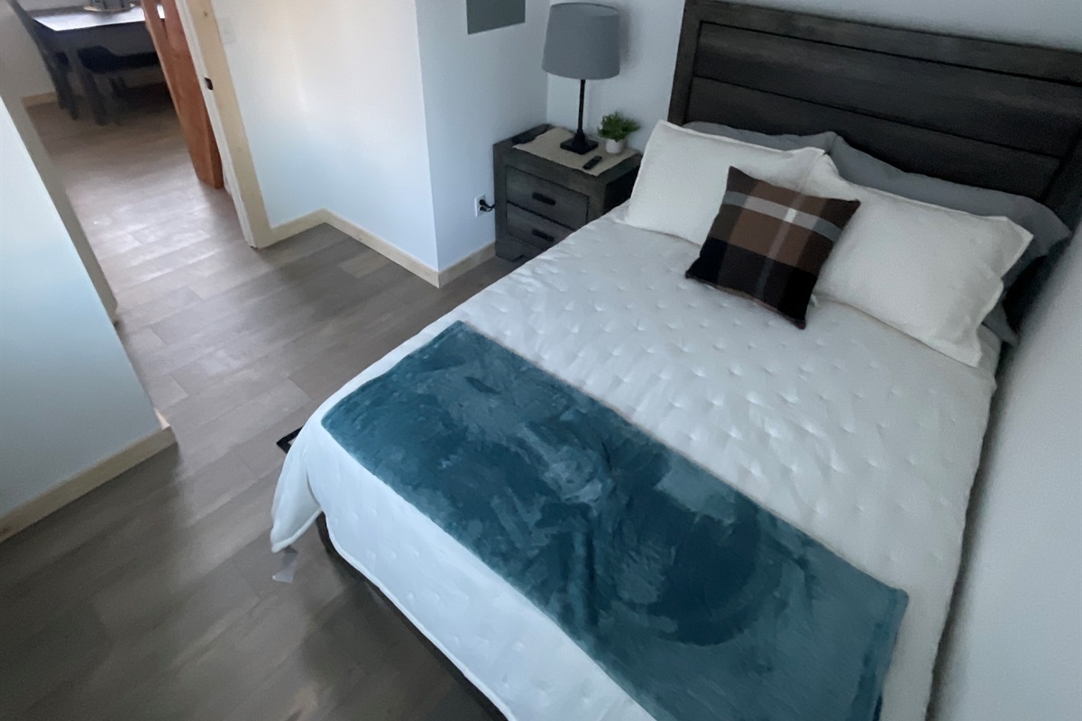 Bedroom on main floor includes a Queen Size Bed with night stand, closet space, and TV. [Photo is representative but may not be from this cabin].