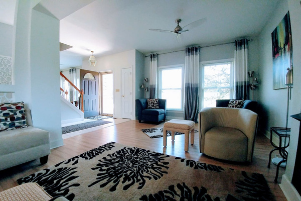 View of 2/3 of the living room from the middle seating area near the fireplace.  Front door and stairs to the second level also.  Lots of light and windows in an open floor plan.