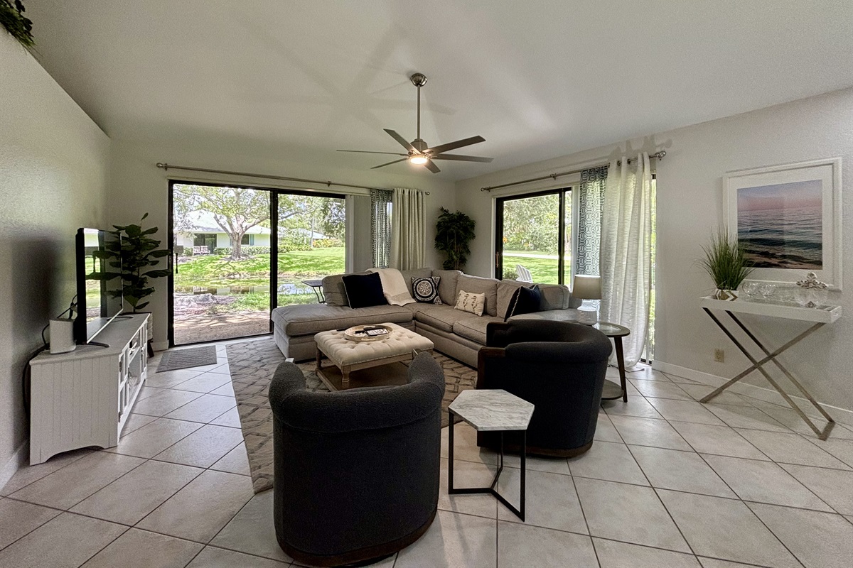 Our large, open living room has seating for six in front of the TV. Two large sliding glass doors let in plenty of light and views of the surrounding, peaceful landscaping.