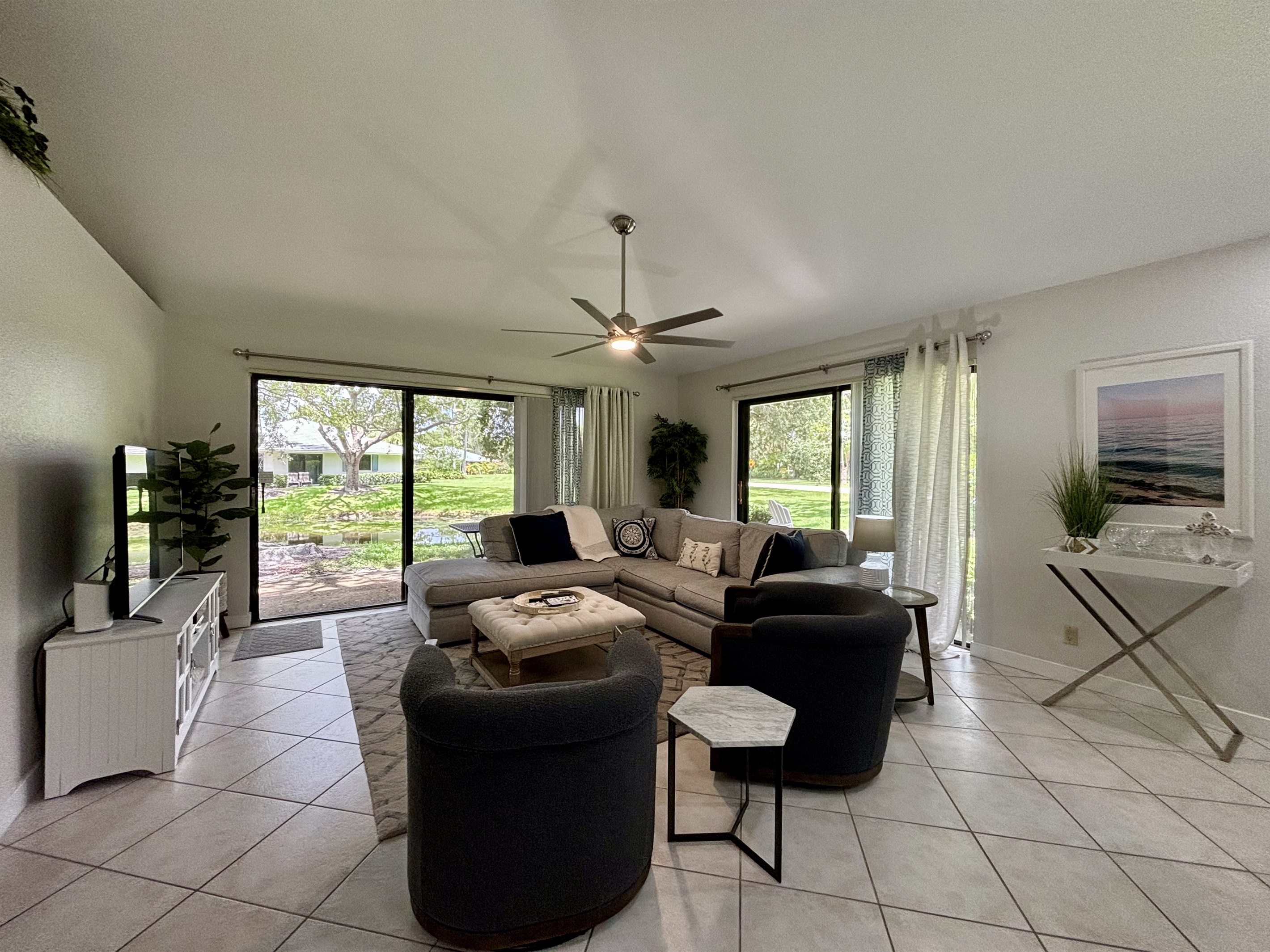Our large, open living room has seating for six in front of the TV. Two large sliding glass doors let in plenty of light and views of the surrounding, peaceful landscaping.