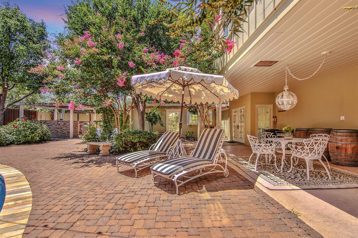 Soak up the sun in this glamorous poolside retreat, featuring a sparkling black swimming pool, lush foliage, and stylish lounge furniture.