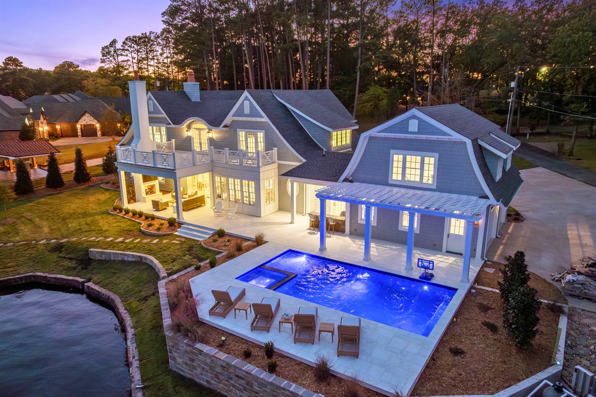 Evening exterior featuring pool lighting and classic architecture.