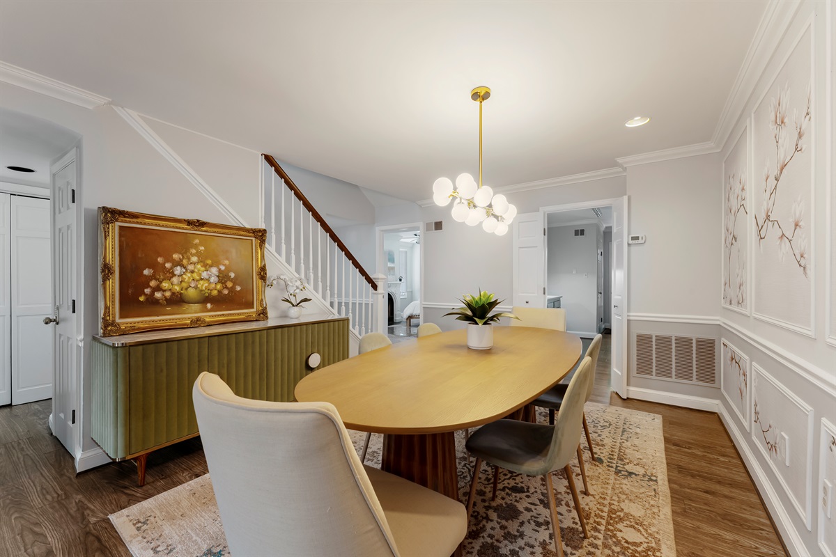 Chic dining space with modern chandelier, decorative wall paneling, and curated artwork