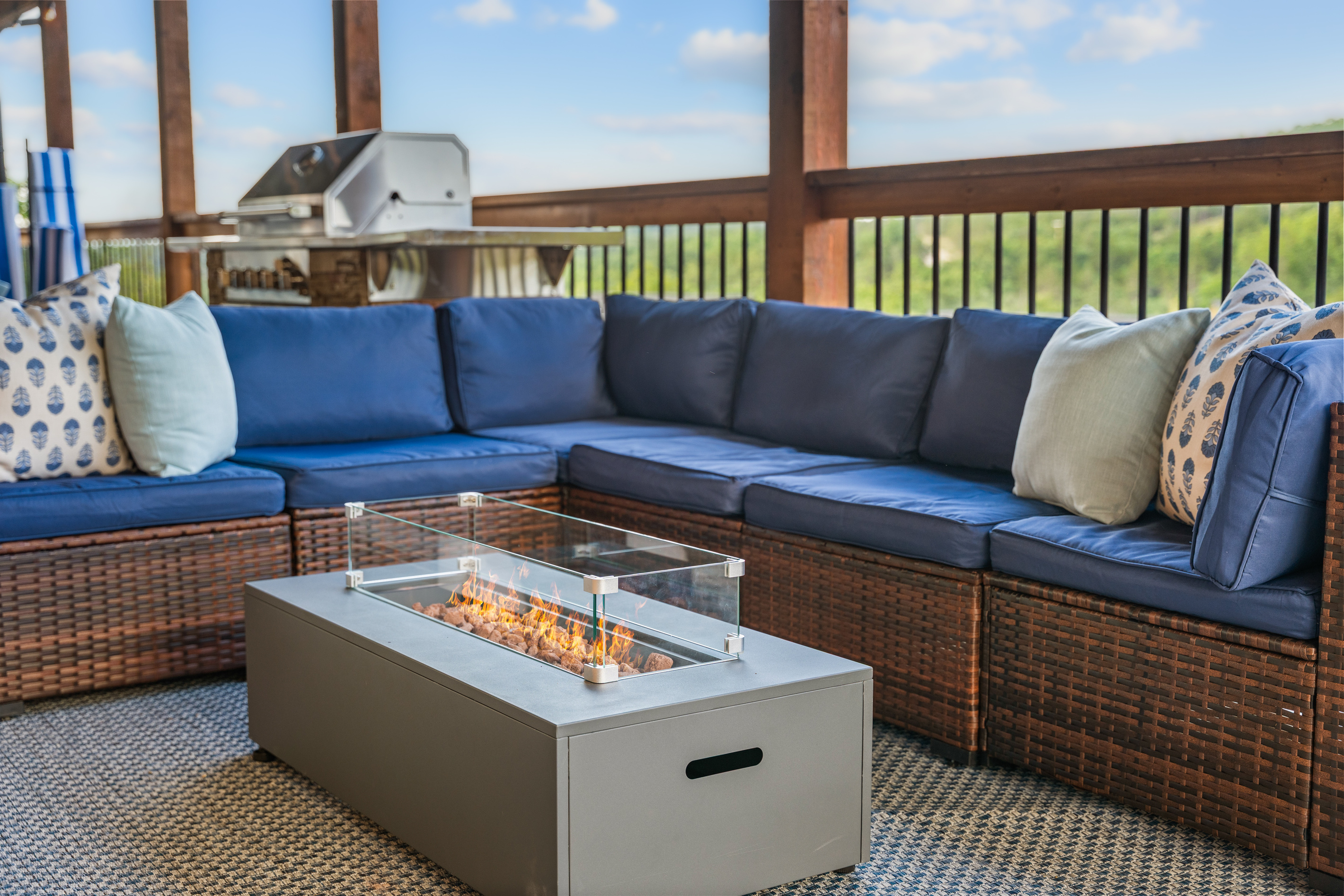 Flames dance behind the glass on the deck's gas fire table, sofa cushions pulled in close.