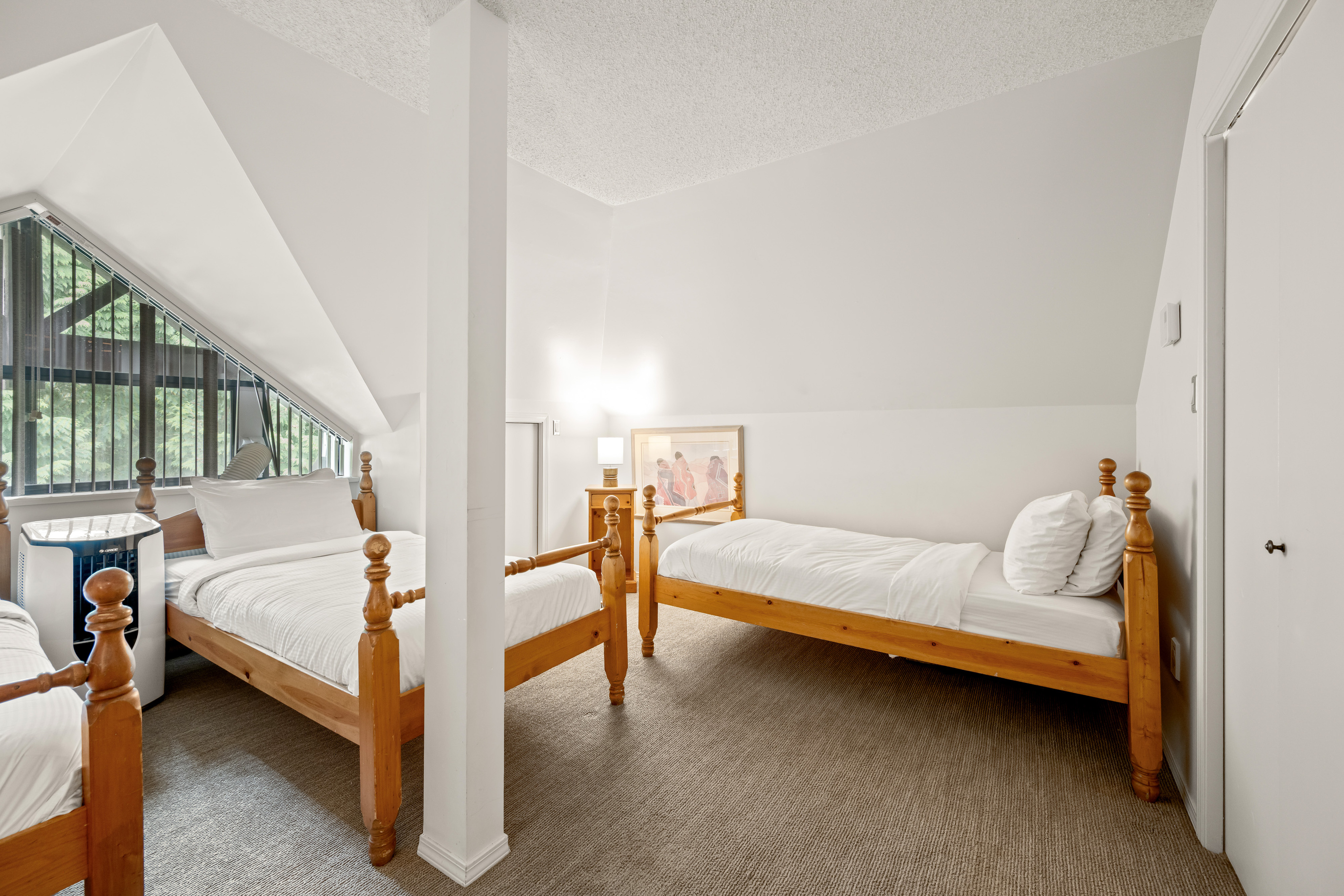 Top-floor loft bedroom (no door) with twin beds under a sloped ceiling; the largest room in the home at 220 sq ft.