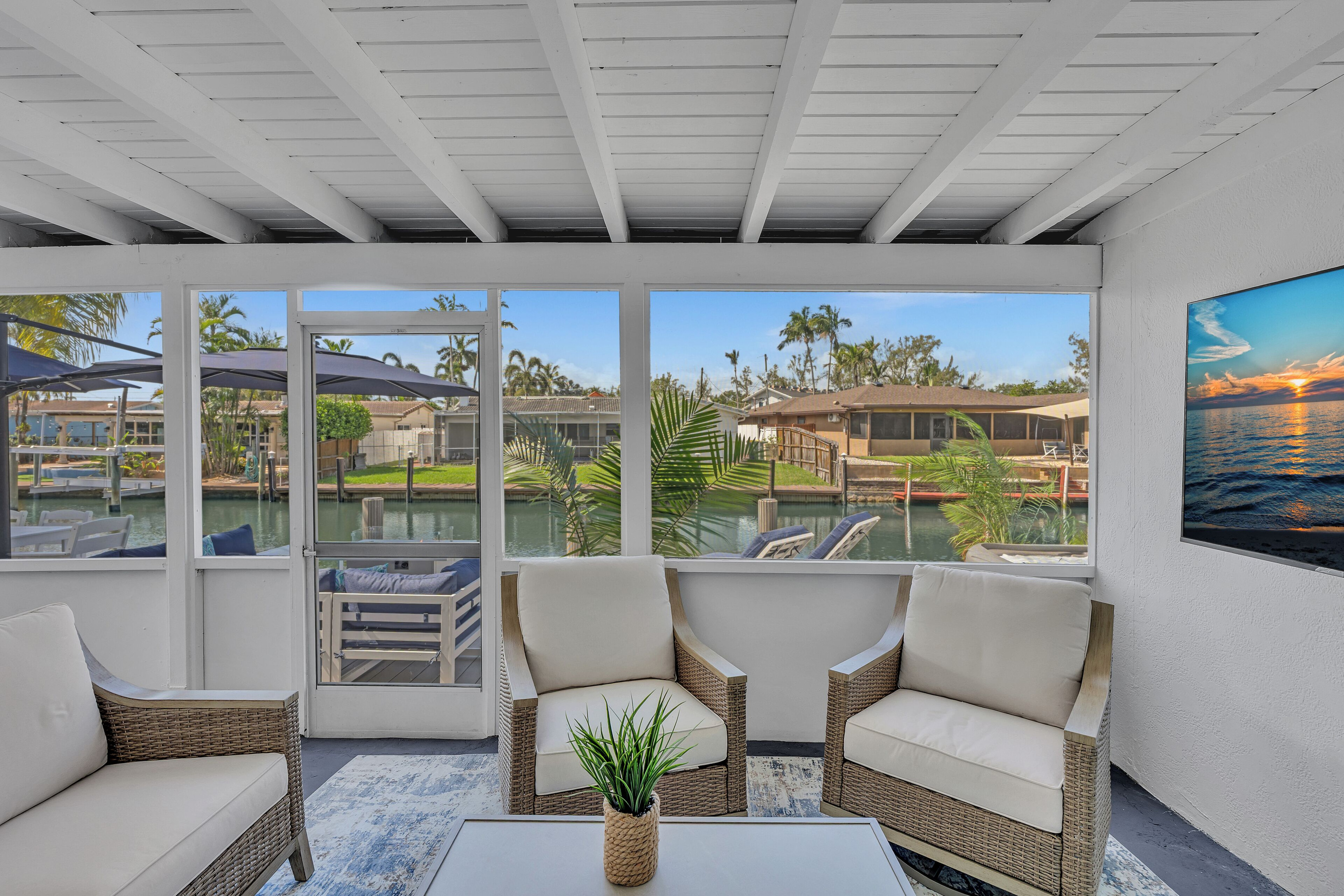Relax in the covered waterfront patio with comfortable seating, a TV, and peaceful canal views.