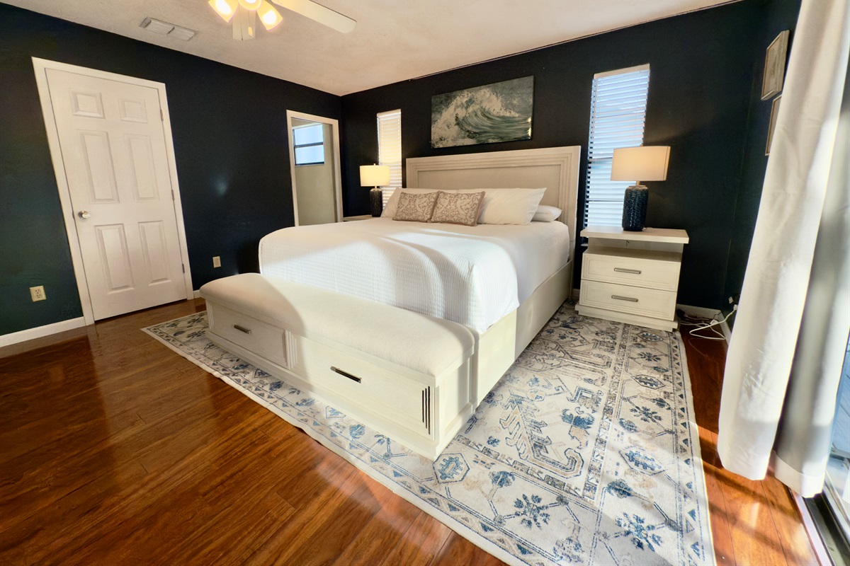 Featuring a luxurious king-size bed framed by a plush upholstered headboard and footboard with built-in storage, this room blends functionality and elegance effortlessly.
