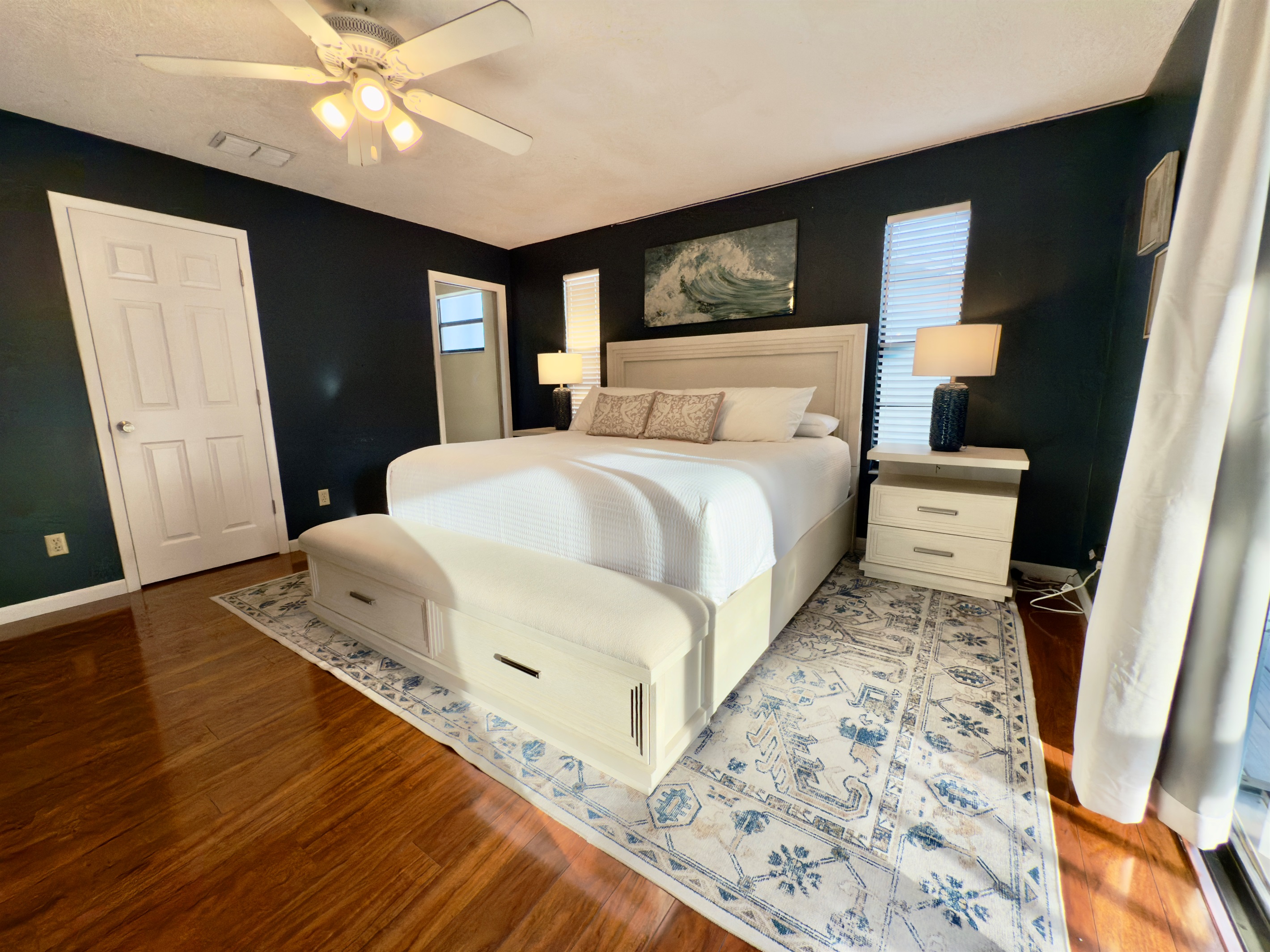 Featuring a luxurious king-size bed framed by a plush upholstered headboard and footboard with built-in storage, this room blends functionality and elegance effortlessly.
