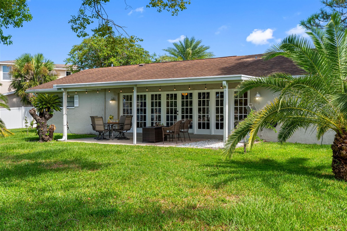 This covered patio offers a quiet retreat, complete with a fire pit and a charming view of the canal, surrounded by lush greenery.