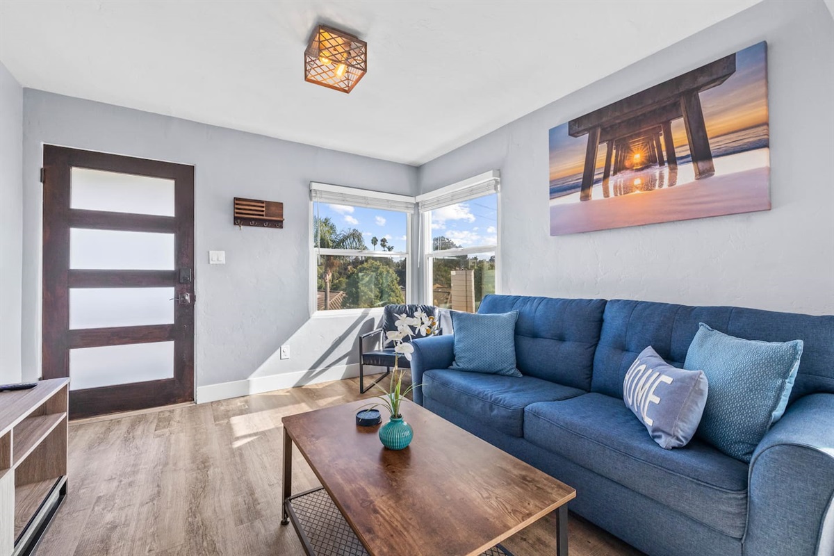 Experience comfort in our inviting living room, complete with a TV, elegant sofa bed, lovely decor, and lush indoor plants. Natural light from the window adds warmth to this charming space.