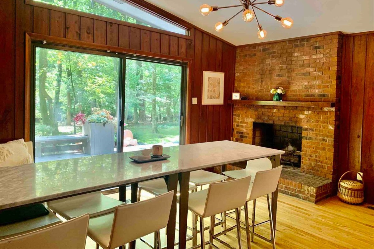 Gather around the marble table under the sputnik light, with a wall of glass framing the woods and a brick fireplace at your back &mdash; mid-century dinner parties, sorted.