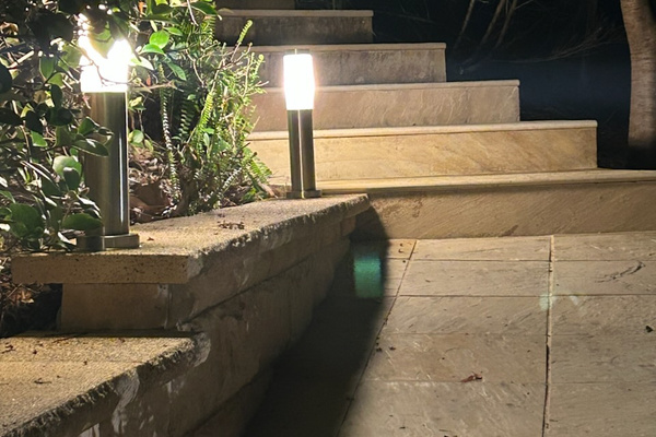 The outdoor steps at Carinya Coastal Escapes are lined with garden lighting, connecting the entry path through the landscaped surrounds.