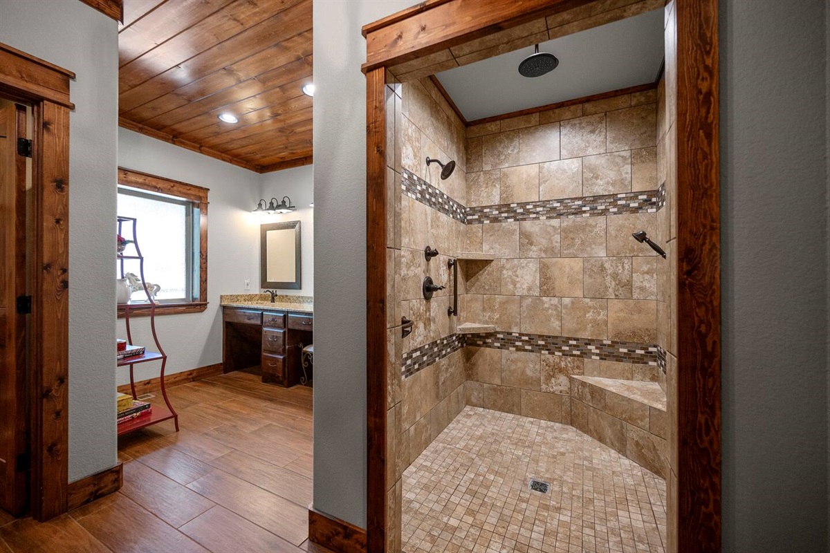 Primary bathroom has a walk in open shower with handrails and a rain shower head