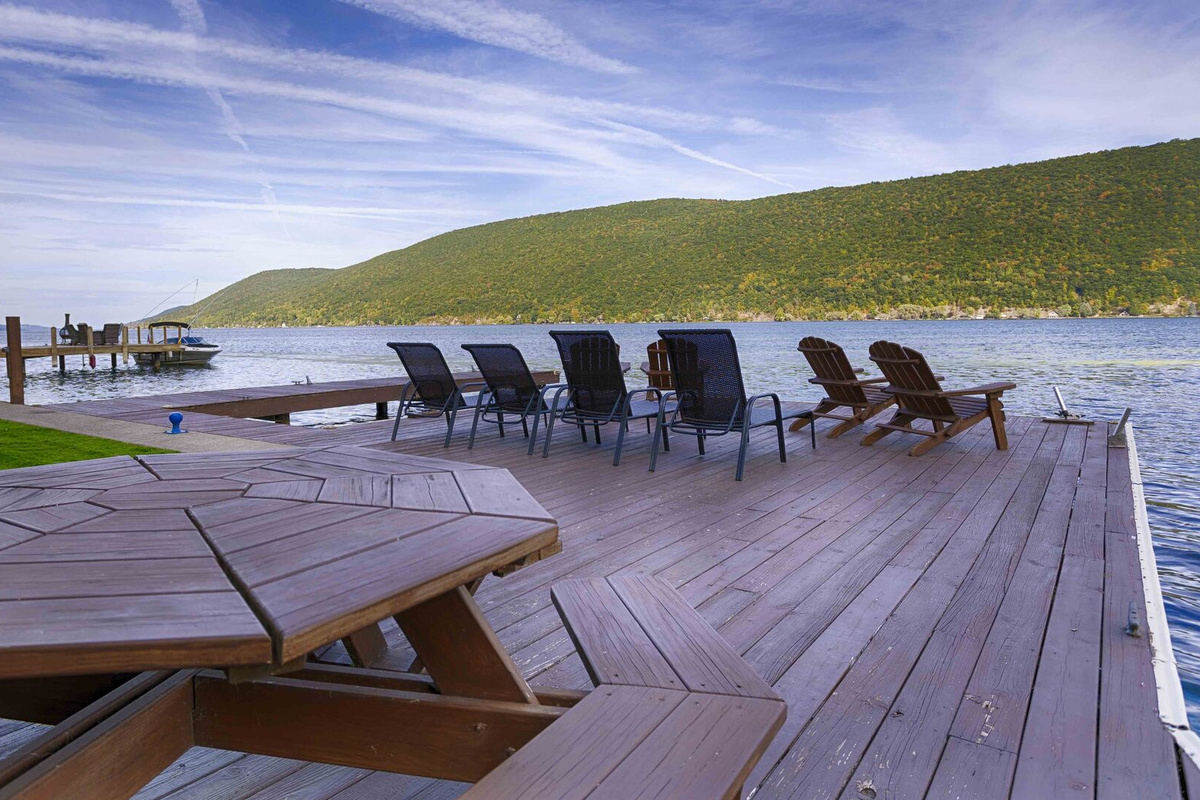Set against the backdrop of tranquil waters, this picturesque dock features a beautiful dining area perfect for outdoor meals or gatherings. A large, sturdy dining table sits in the center, surrounded by comfortable, weather-resistant chairs with plu