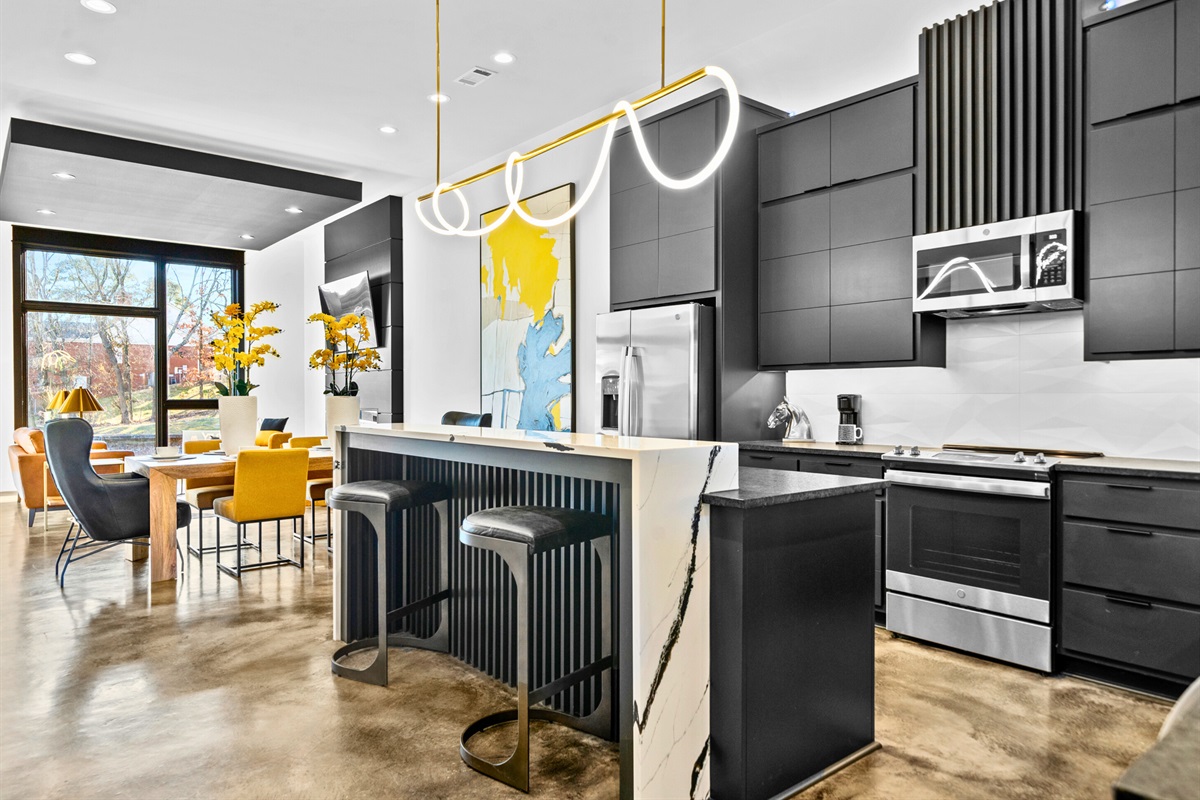 The open kitchen and dining area exude modern elegance, featuring bold lighting, sleek finishes, and a seamless flow designed for entertaining and everyday comfort.