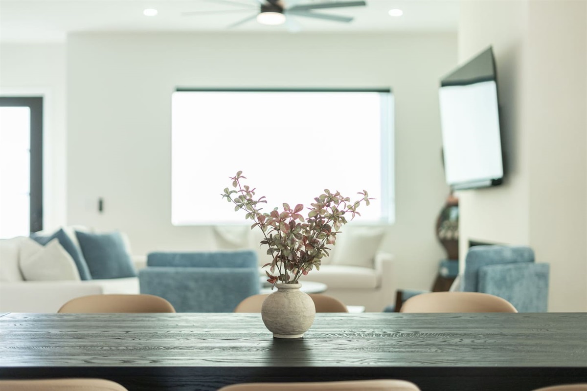 Stylish dining table with a rustic vase centerpiece, set against the bright and airy living area.