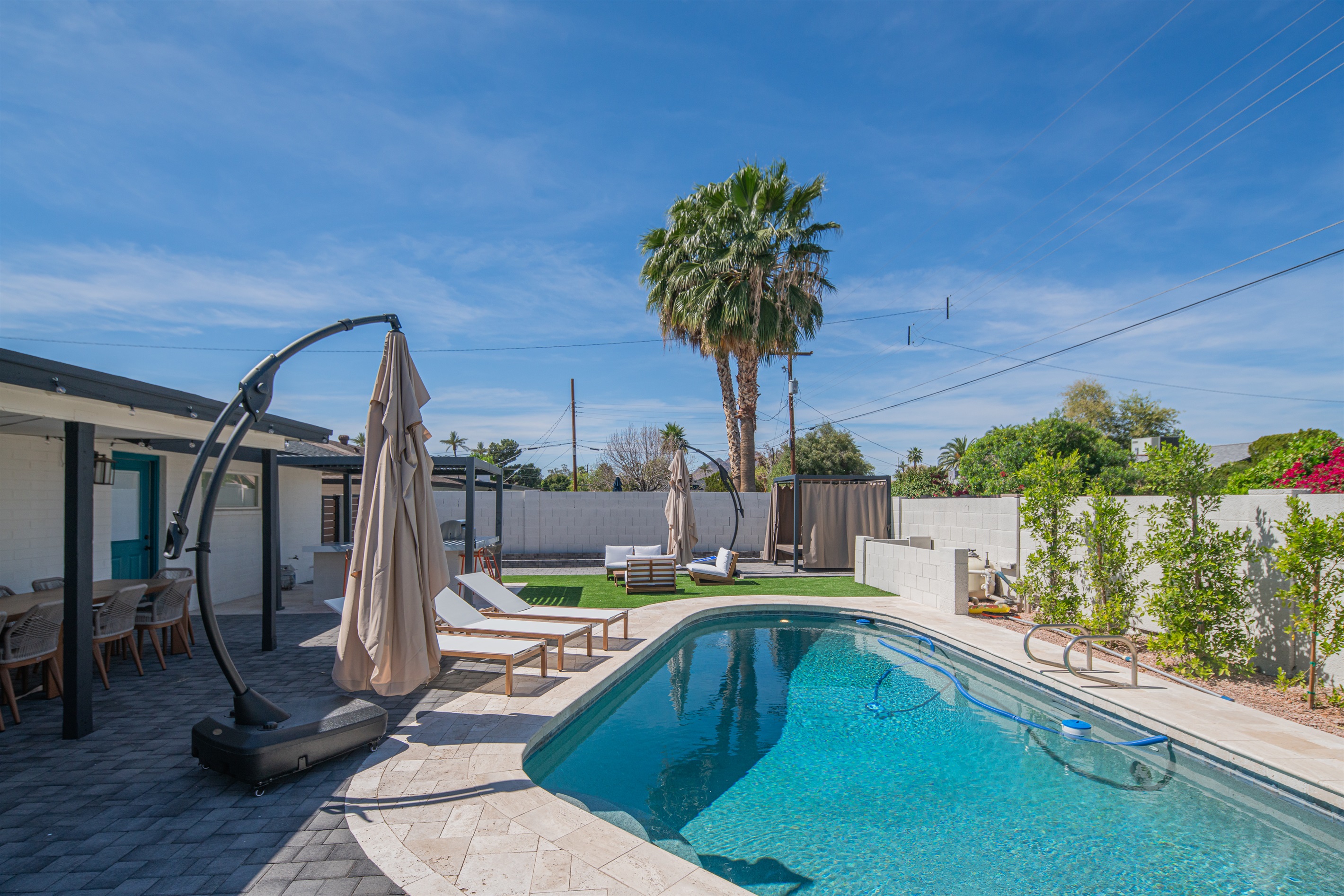 Resort-style pool with loungers, umbrellas, and private backyard setting