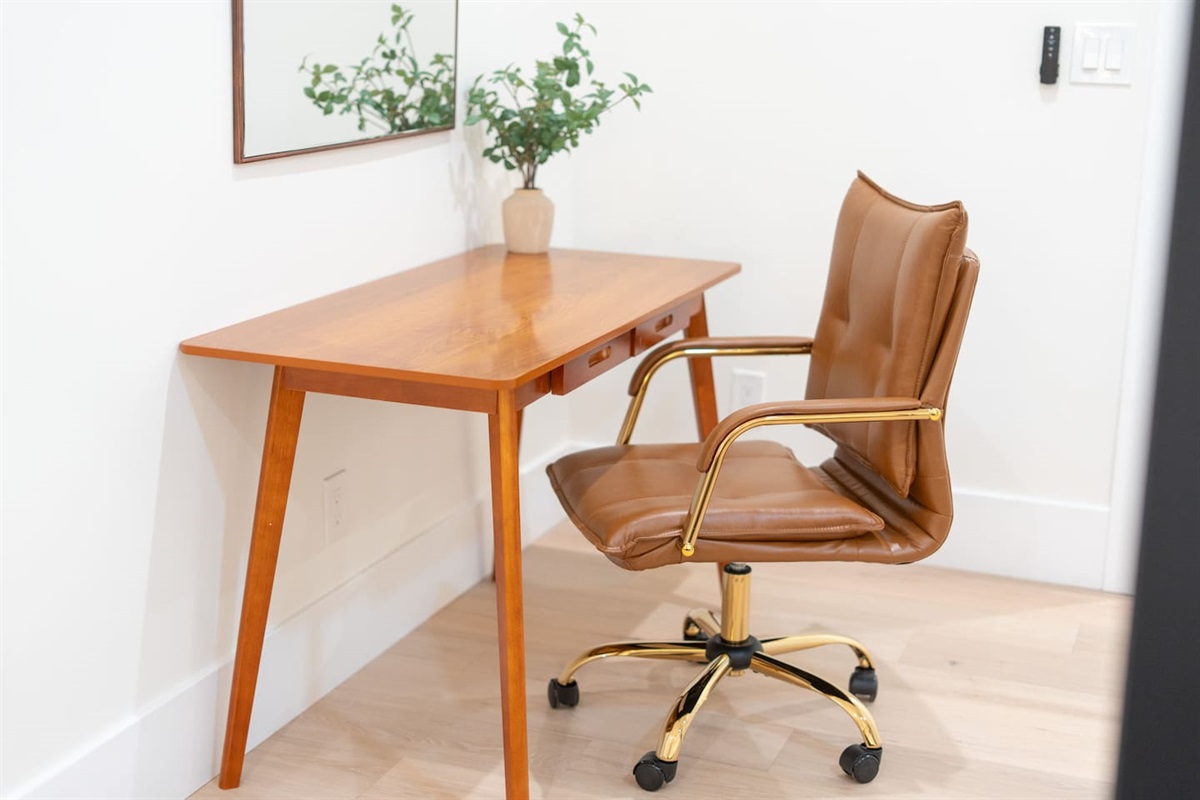 Dedicated workspace with sleek desk, leather chair, and mirror — perfect for remote work or getting ready.