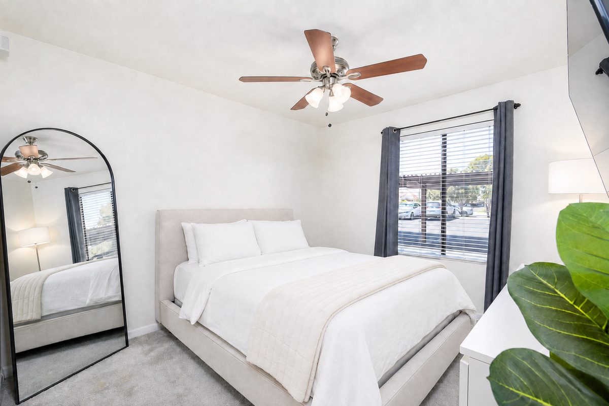 Bedroom with a queen bed, dresser, ceiling fan, and natural light for a comfortable rest.
