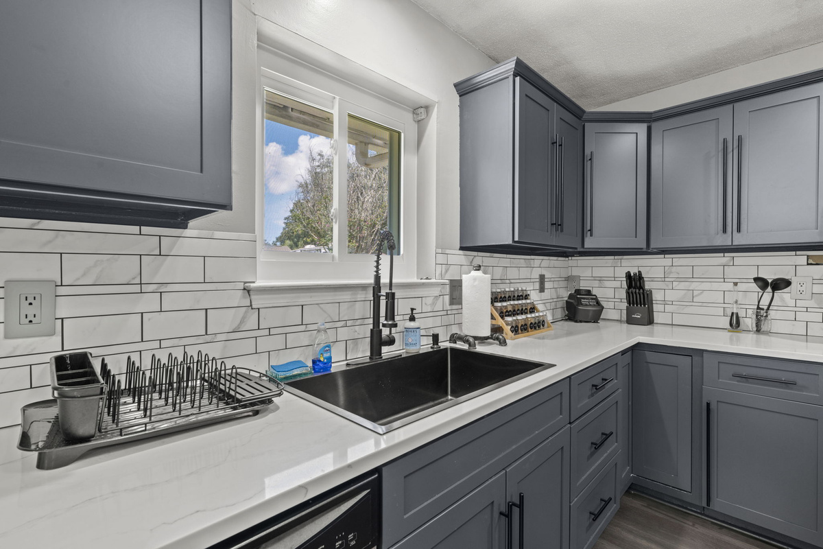 A deep farmhouse-style sink and gooseneck faucet make cleanup a breeze, framed by a classic subway tile backsplash.