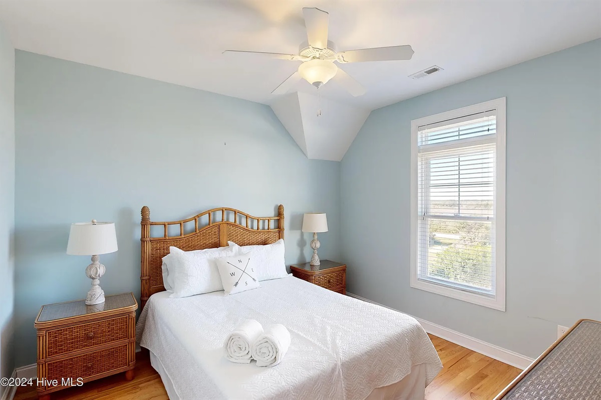 Bright guest room featuring a classic wicker headboard and ample natural light