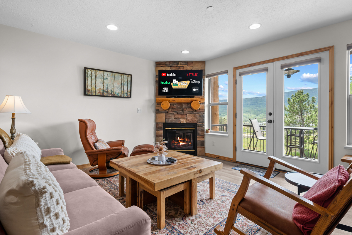 Gather in the inviting living room, where comfort meets views—Smart TV, fireplace, and doors to a mountain-view deck.