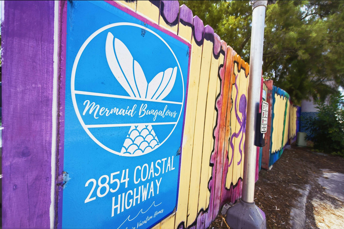 The Mermaid Bungalow sign at 2854 Coastal Highway, hand-painted onto the fence. Look for the mermaid and you have found us; if you cannot see her anywhere then the Publix will be over on your left-hand side.