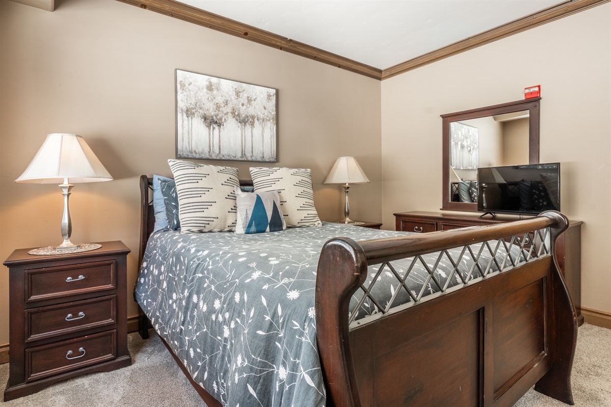 Comfortable queen bedroom with warm finishes and ample storage, ideal for couples or additional adult guests.