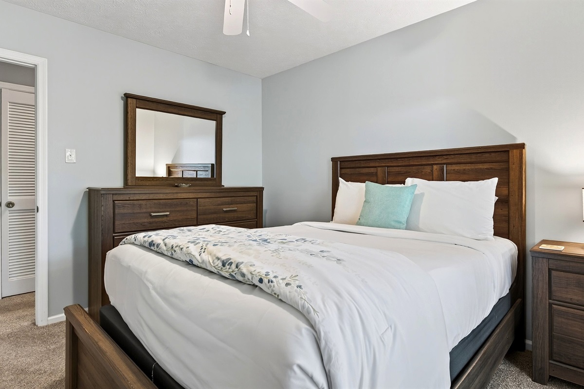 Main level bedroom 3 features a queen size bed.